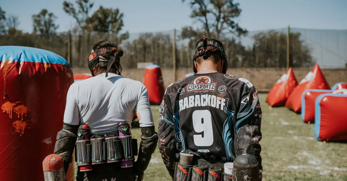 Two paintball players with electronic hoppers loaded on their markers ready for action